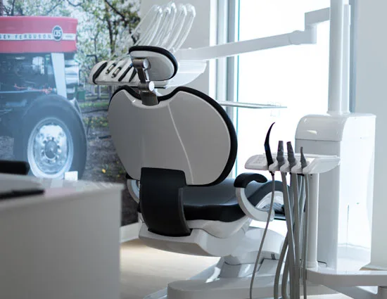 A treatment chair in front of a wall-sized photo of a red Massey Ferguson tractor in the orchard